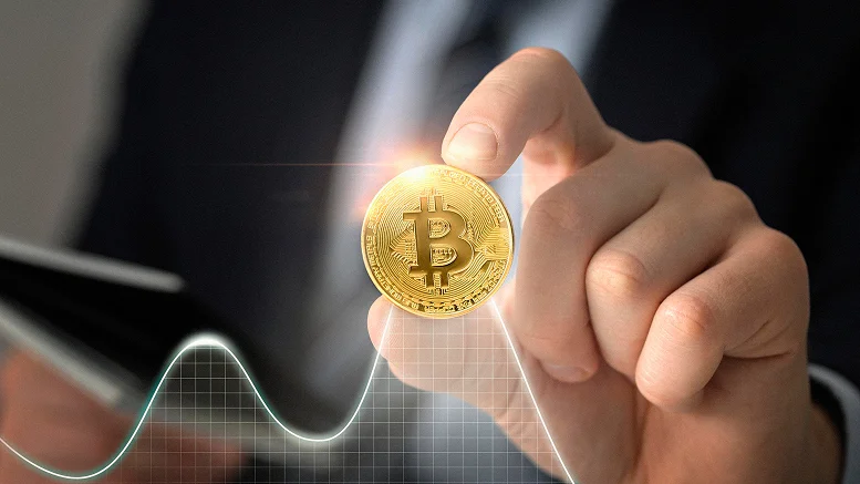 Businessman holding a Bitcoin coin with a rising market graph in the foreground, symbolizing Bitcoin investment trends and speculation.