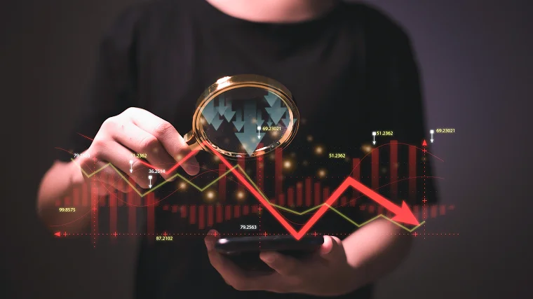 Magnifying glass highlighting downward market trends to represent the risks involved in being a CFD broker